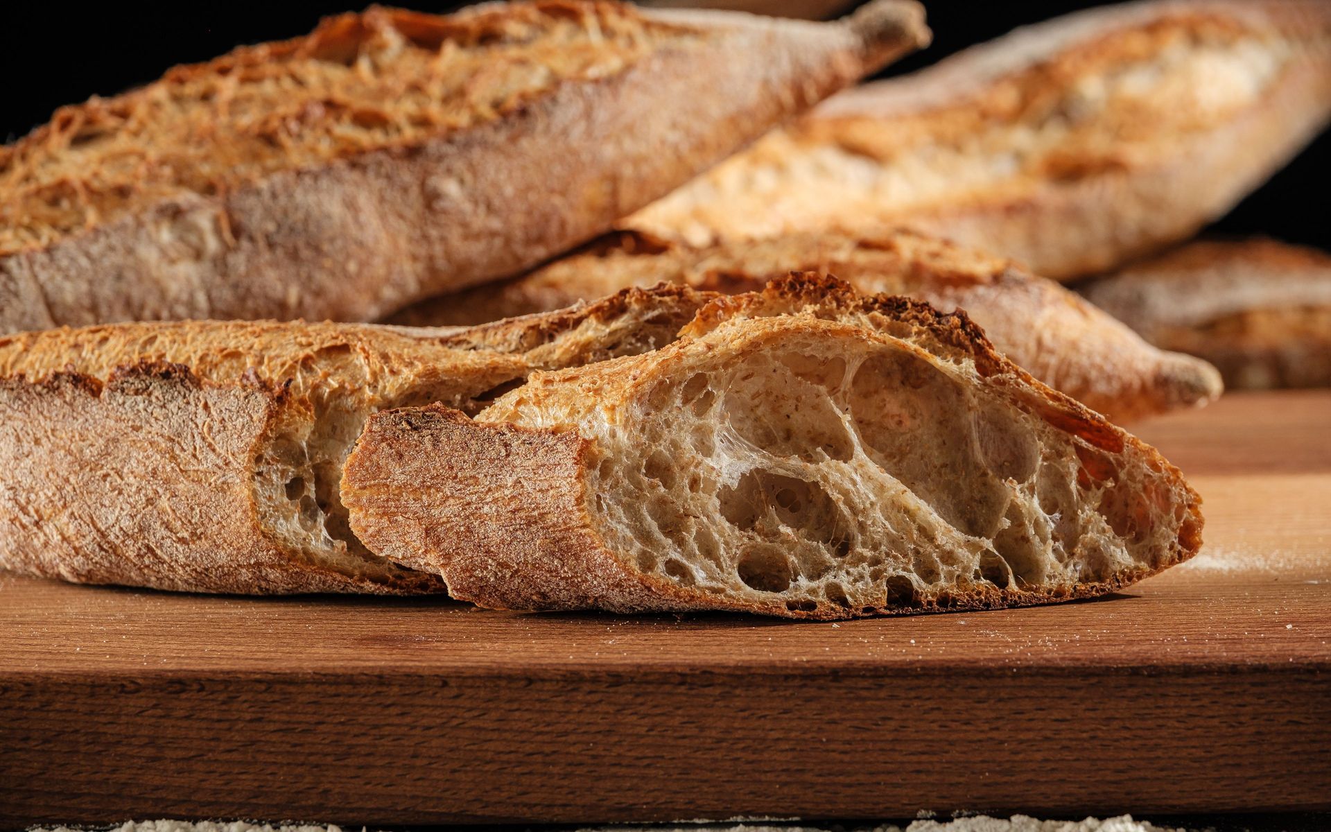 Wholegrain baguette with crisp crust and open, airy crumb on wooden board