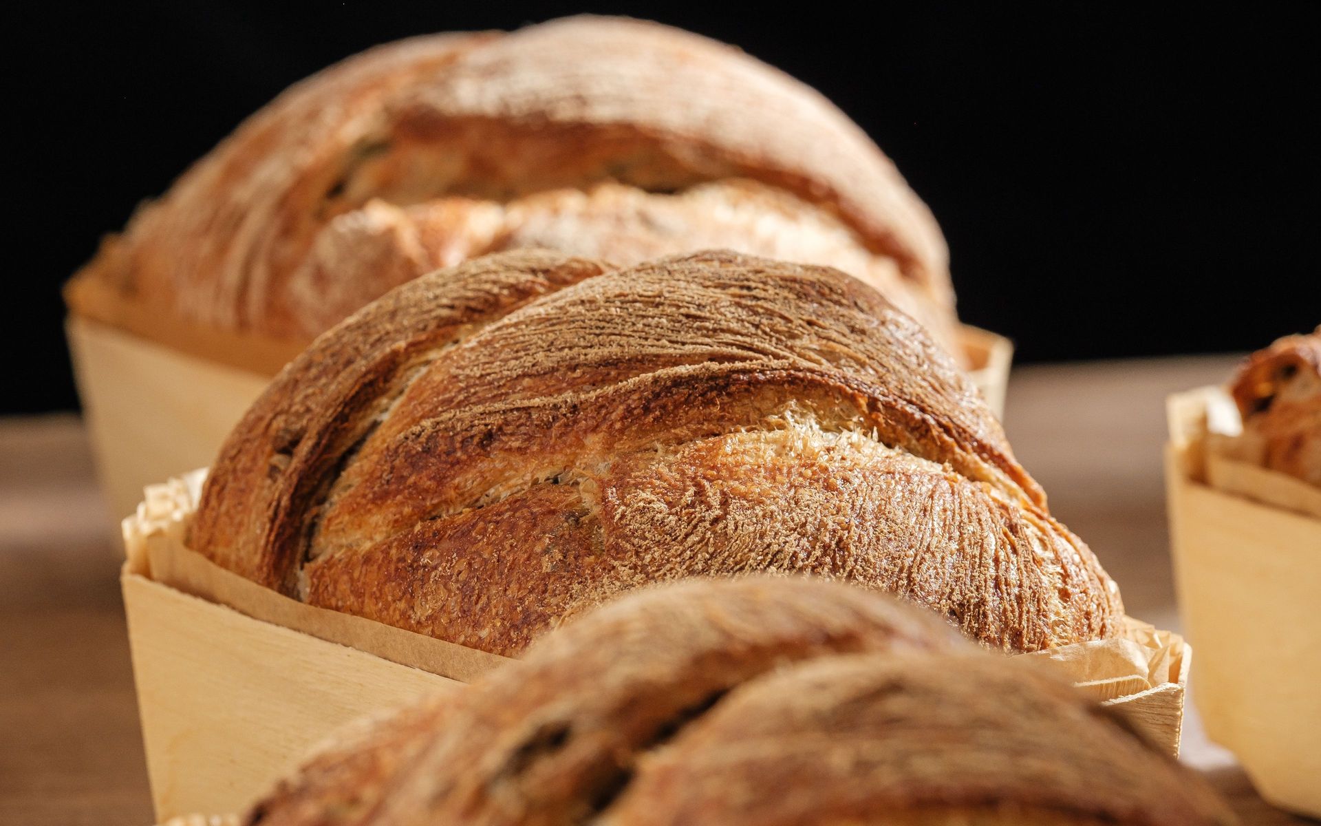 Rustic wholegrain loaf (sourdough) with crisp crust in wooden baking mold