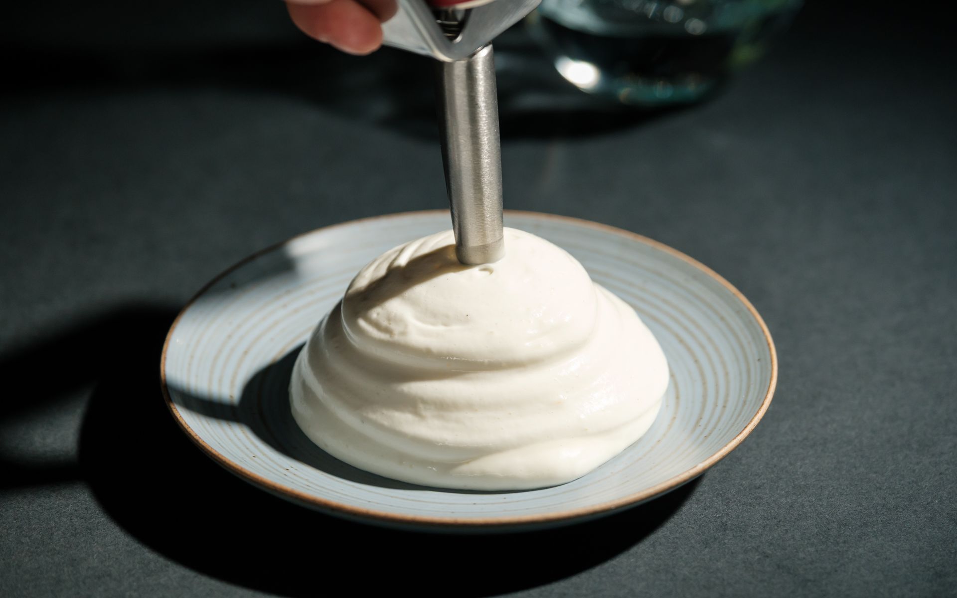 Parmesan espuma, white airy cheese foam piped from a siphon onto a plate — fine dining plating