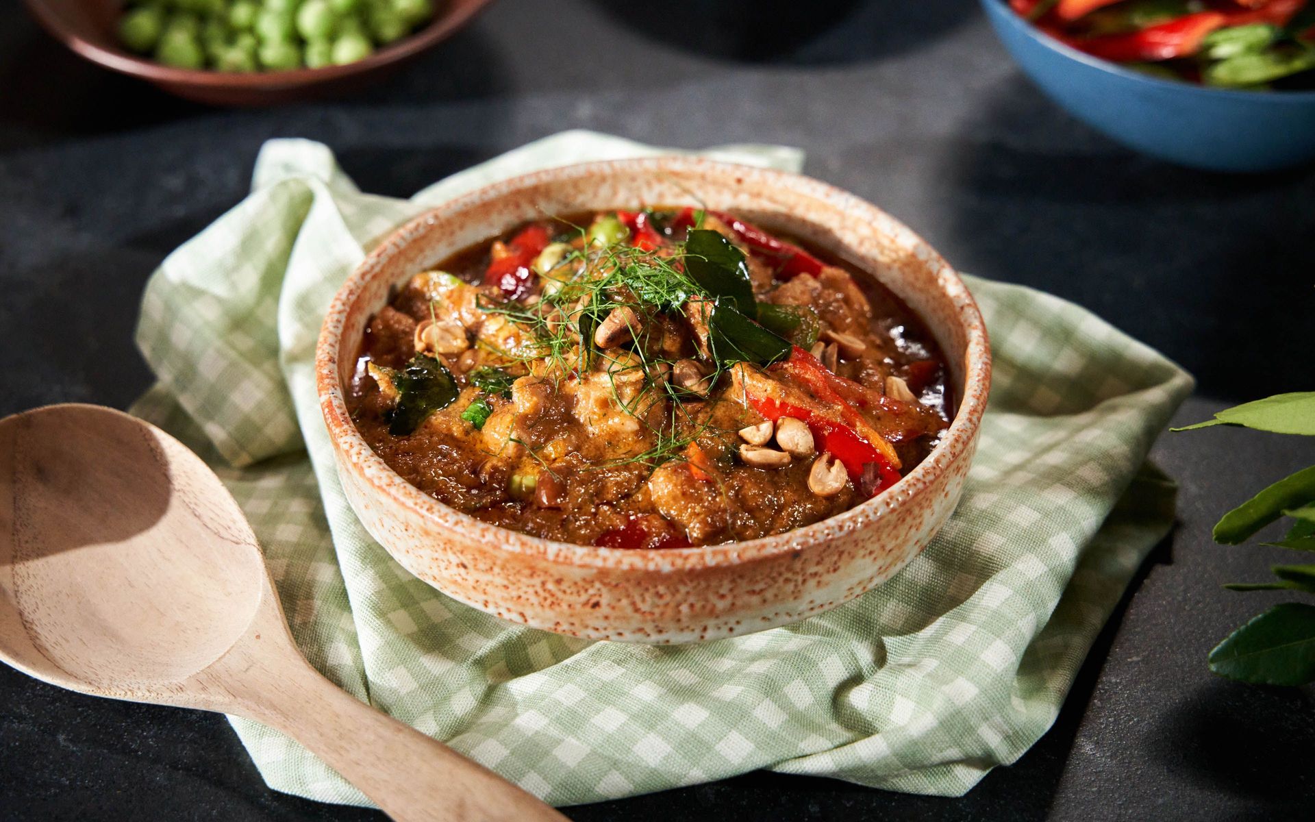Bowl of red Thai curry with vegetables and cashews.