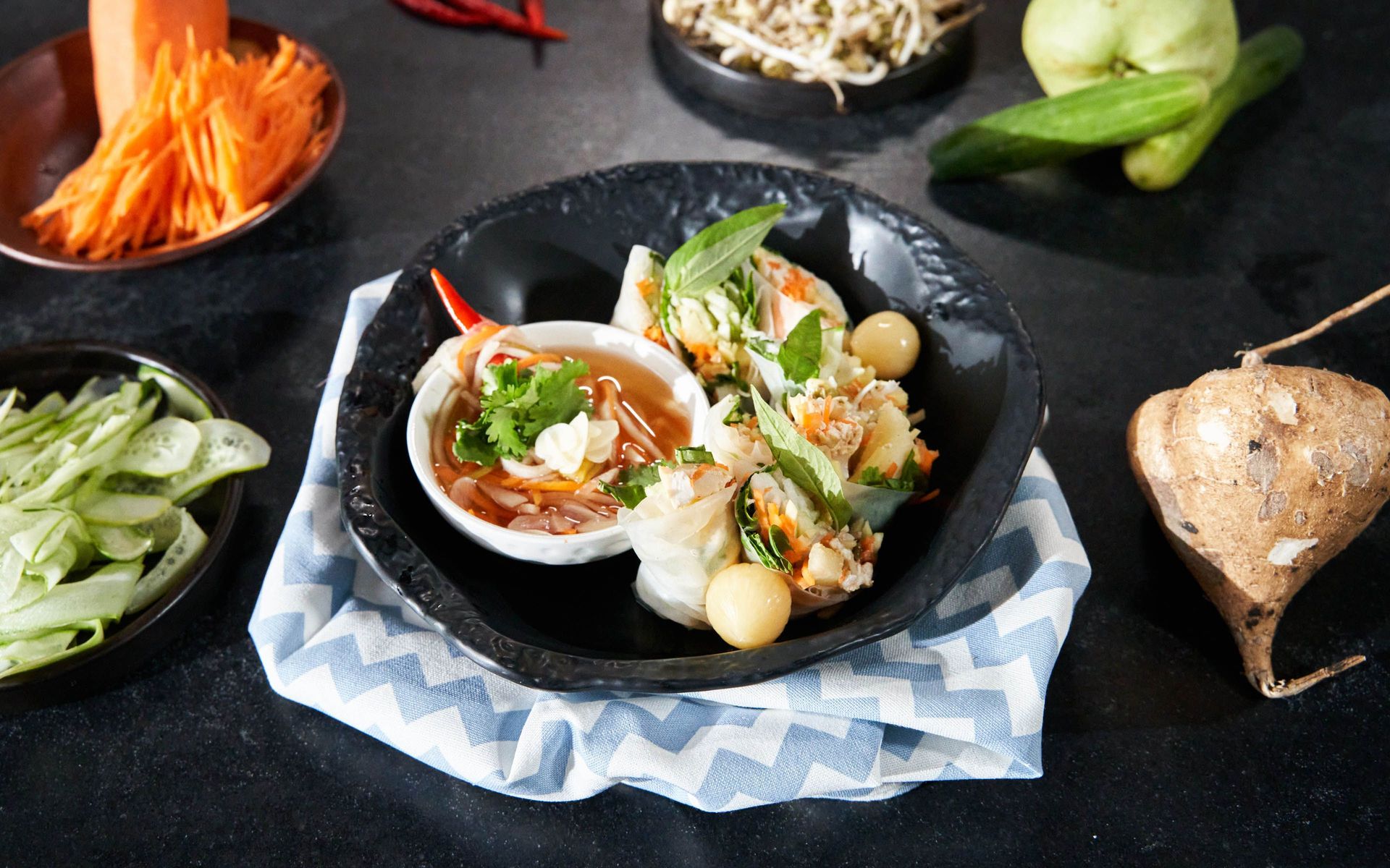 Fresh Thai spring rolls in rice paper with shredded carrot, cucumber, Thai basil and sweet-chili dipping sauce